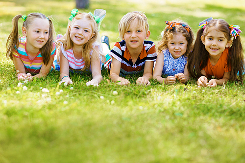 Adorable group of children lying on green grass