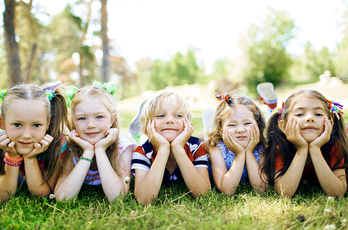 Row of friendly kids lying on the lawn