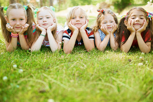 Group of friendly kids lying on the lawn