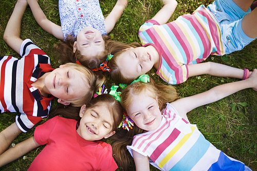 Relaxing kids with closed eyes lying on ground