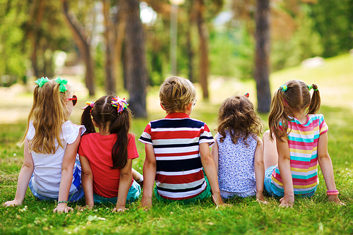 Rear view of children sitting together in the park