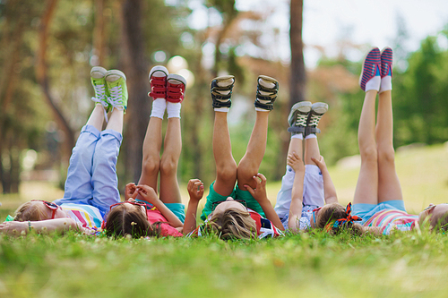 Kids with raised legs lying in row