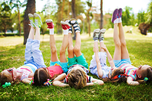 Children lying on the grass with their feet raised