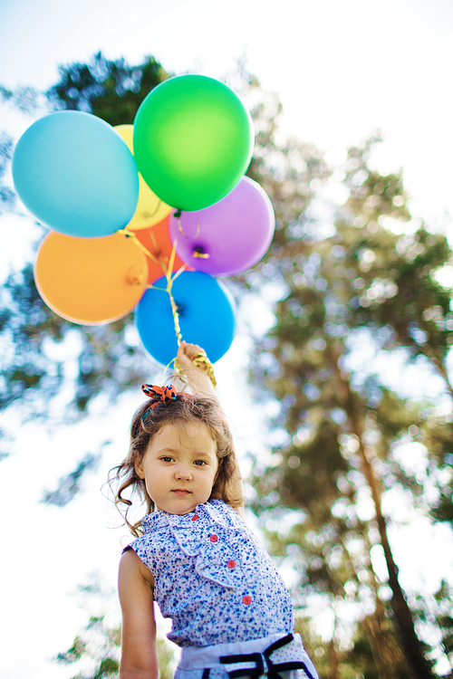 Portrait of cute little girl with colorful balloons outdoors