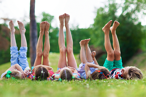 Friendly children with raised legs relaxing on grass