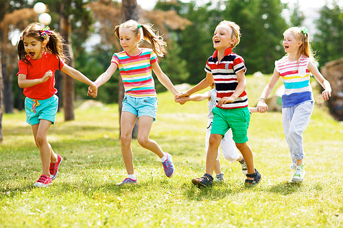 Cute children running down green lawn in park