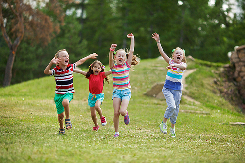 Ecstatic kids running down green lawn