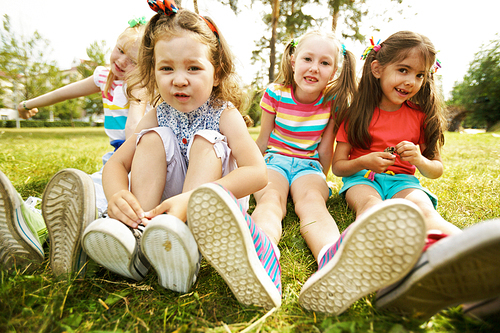 Group of relaxed girls sitting on grass in park