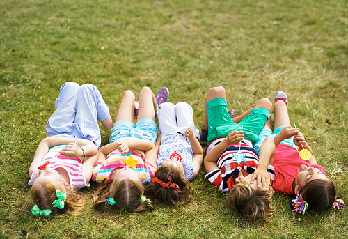 Cute kids with lollipops lyin on grass