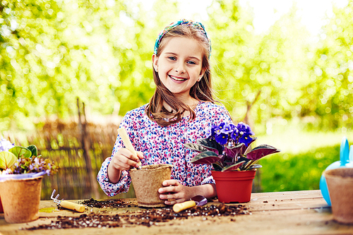 Portrait of little girl planting a violet in flowerpot