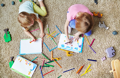 Little sisters drawing and coloring pictures in kindergarten