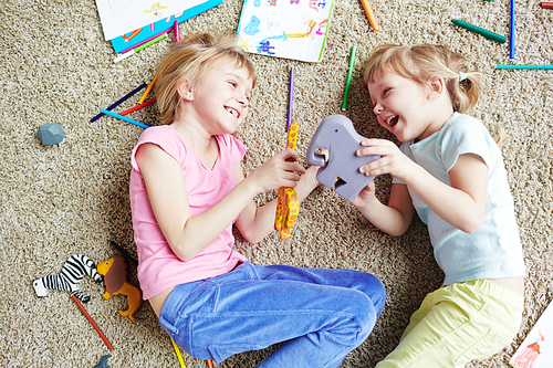 Happy siblings playing with toy animals on the floor