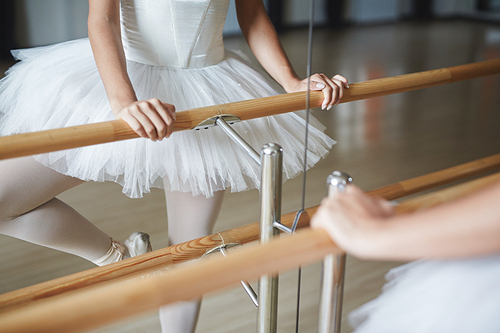 Ballerina holding wooden handrail during repetition