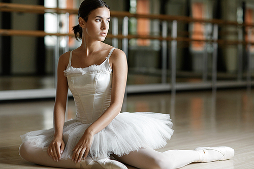 Relaxed ballerina sitting on the floor of class