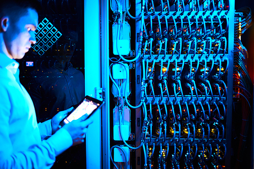 Computer researcher with touchpad standing by data storage