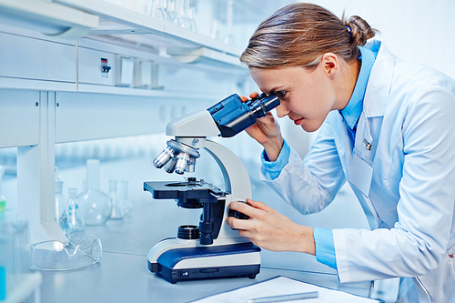 Female scientist looking through a microscope in laboratory