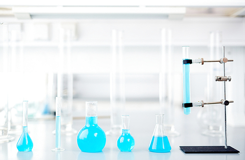 Row of glassware with blue liquid on laboratory table