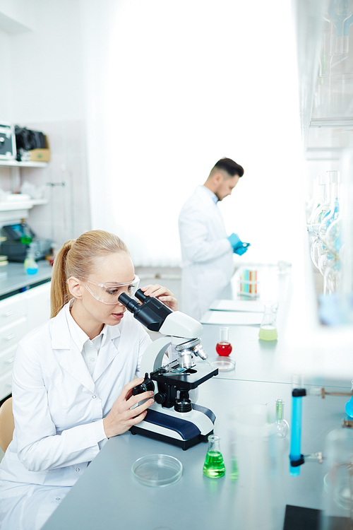 Professional scientist looking in microscope in chemical lab