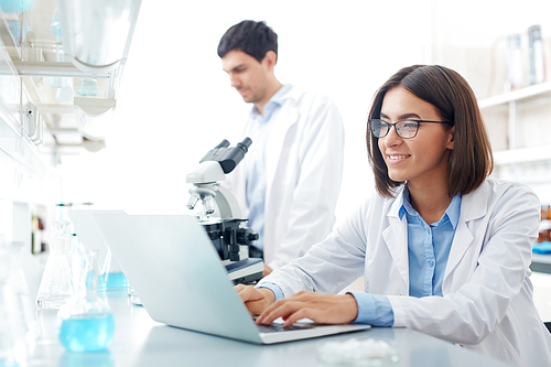 Lab worker sitting in front of laptop and searching for data for new experiment