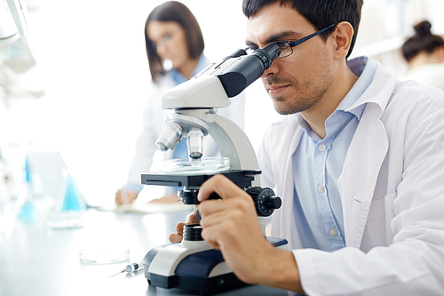 Young man looking in microscope in scientific laboratory