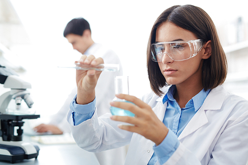 Female scientist testing chemical liquids and mixing them