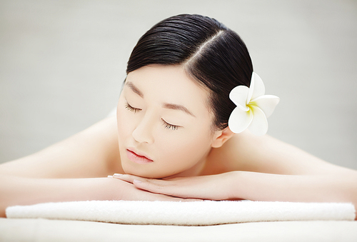 Young Asian woman with closed eyes relaxing in spa salon