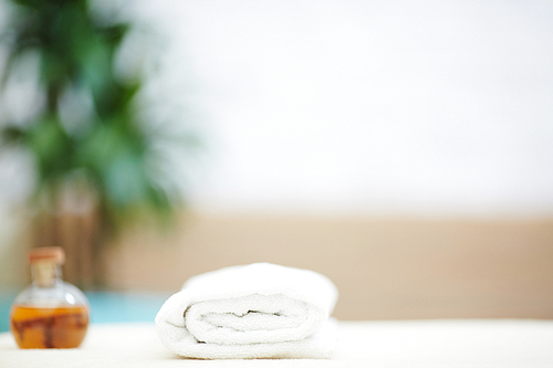 Folded white towel and bottle of aromatic essential oil