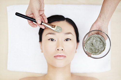 Young Asian woman having peeling procedure in spa salon