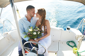 Amorous bride and groom traveling on yacht during honeymoon