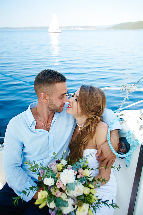 Embracing newlyweds looking at one another during romantic voyage on yacht