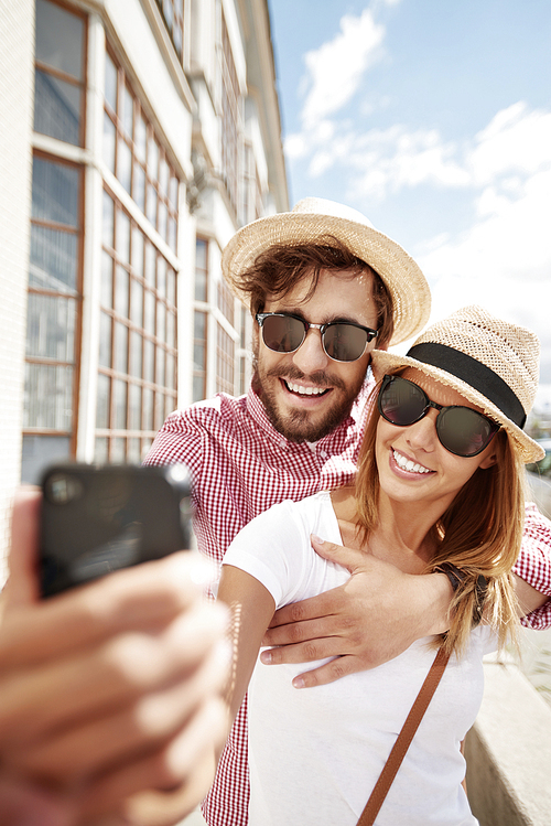 Loving couple taking selfie on smartphone outdoors