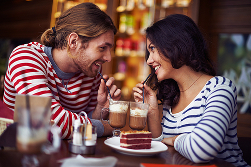 Happy young couple enjoying dessert in cafe
