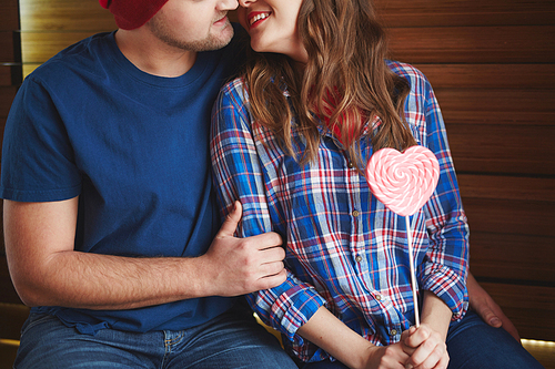 Amorous woman with heartshaped candy flirting with young man