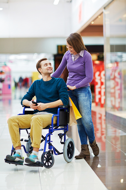 Disabled young man looking at his girlfriend in shopping center