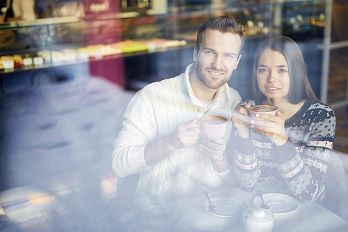 Restful couple having hot coffee in cafe