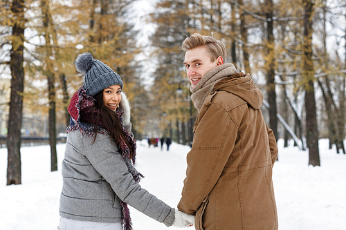 Amorous couple holding by hands during walk on winter day