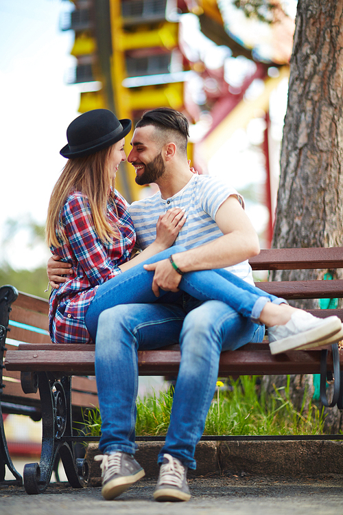 Flirting couple sitting on bench in park