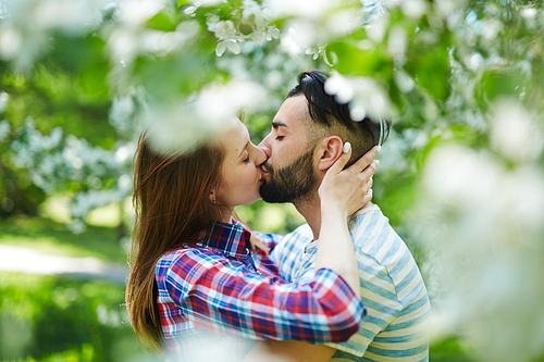 Young couple kissing in blooming garden
