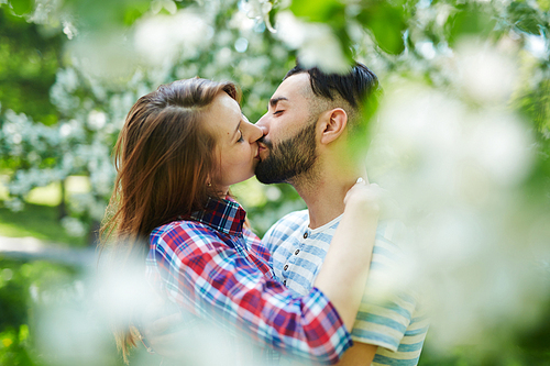 Amorous girl and guy kissing in park