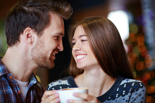 Young couple looking at one another while having coffee