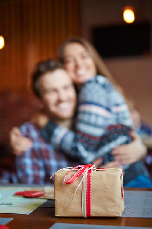 Wrapped gift in box on background of embracing couple