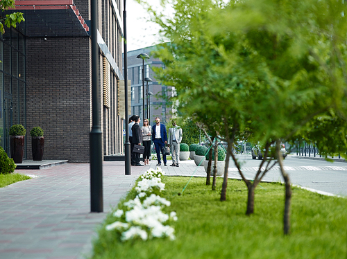 Young employees communicating outdoors by modern office building