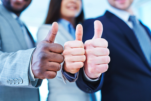 Thumb up gesture shown by three business partners