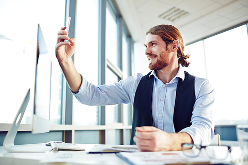 Young businessman making selfie at workplace