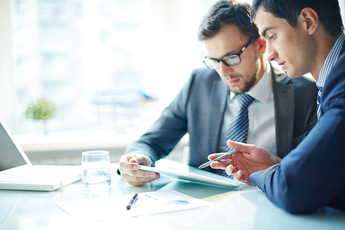 Two business partners working in team and using computer at the table