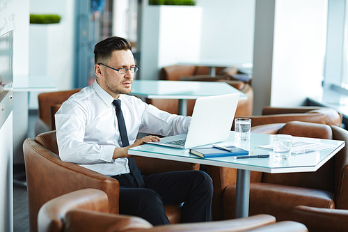 Young businessman sitting in cafe in front of laptop