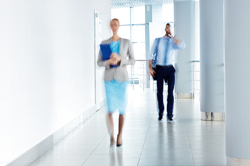 Blurred image of business people walking along the office corridor