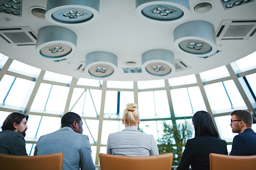 Rear view of managers sitting in row in conference hall