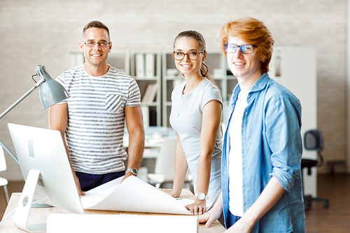 Group of young architects standing by their workplace