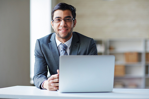 Portrait of manager sitting at the table and smiling at camera